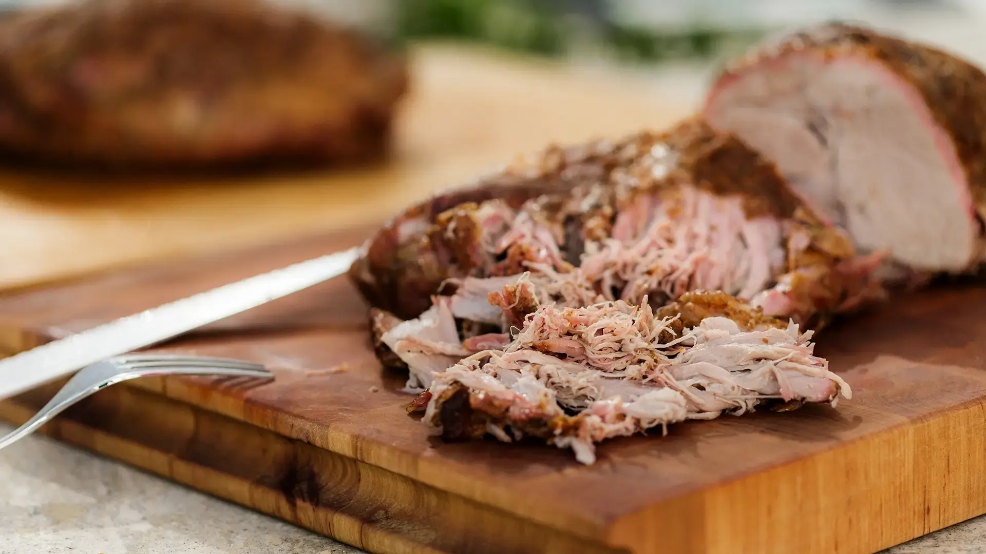 Bayerisch Pulled Pork aus dem Smoker, serviert auf heißem Granitstein mit Sauerkraut, Äpfeln und Laugenbuns